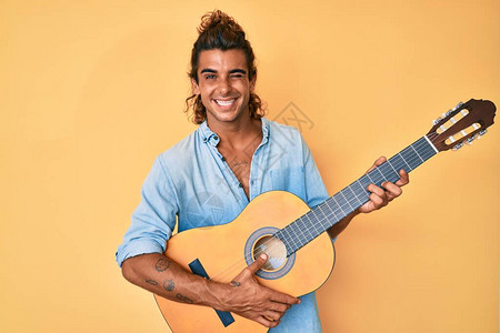年轻西班牙人玩古典吉他用感的表情欢乐和快乐的面孔对图片