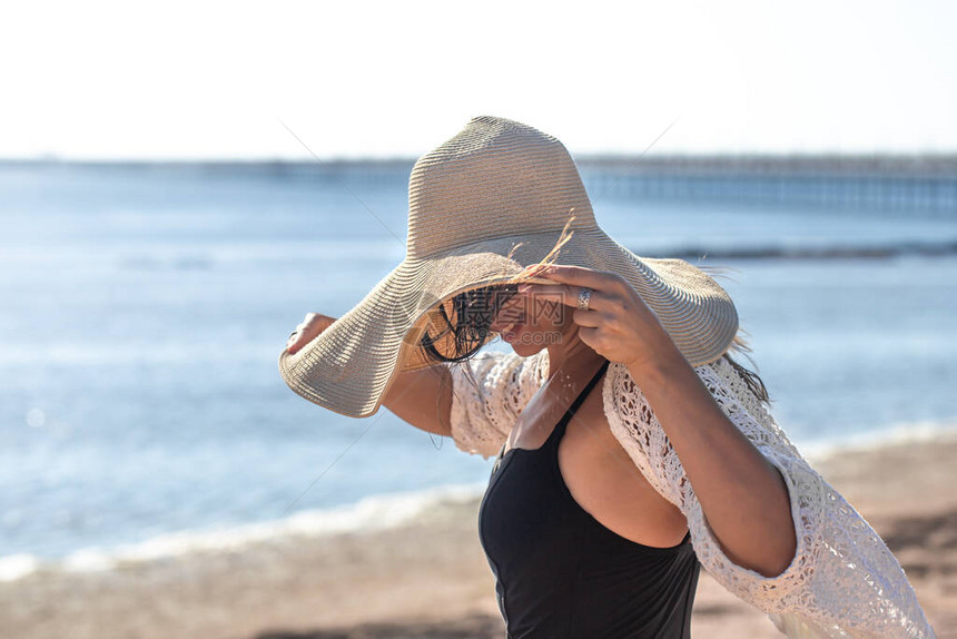 一个穿着帽子和泳衣的漂亮女人在海边图片