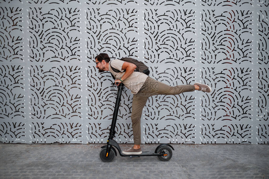 驾驶电动滑板车穿越城市的乐趣一个时髦的人喜欢在夏天的日落时分穿过城市生态风格和乐趣在城市中移动图片
