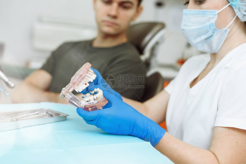 满意的病人坐在牙医的椅子上牙医在诊所向病人解释人造牙齿男子在图片