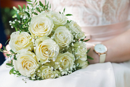 美丽的一束精美的白玫瑰花束在新娘手中图片