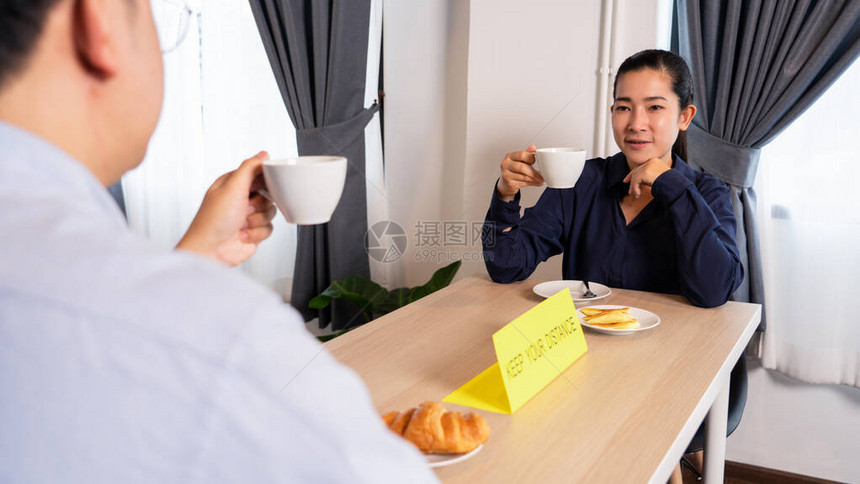 亚洲夫妇坐在餐厅里分开吃饭图片