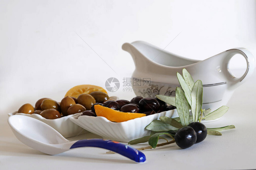 白底碗里的黑橄榄和地上的橄榄枝图片