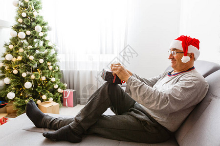 坐在离子边上坐在家里圣诞树背景的微笑着的caucasia图片
