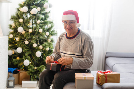 坐在离子边上坐在家里圣诞树背景的微笑着的caucasia图片