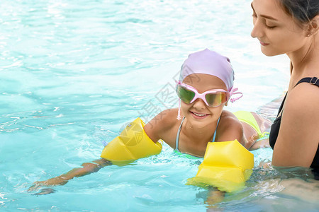 教练小孩在游泳池里游泳图片