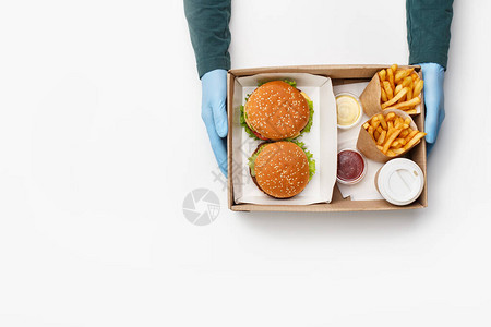 服务员给盒子里有汉堡和芝士汉堡纸包里的炸薯条酱汁和番茄酱图片