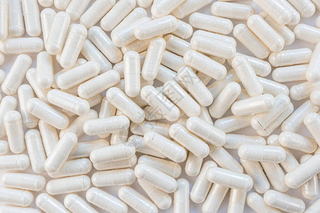 光胶囊特写维生素膳食补充剂的概念白色瓶中的胶囊图片