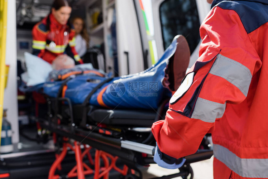 穿制服带病人在户外救护车中携带担架和病人的护理人图片