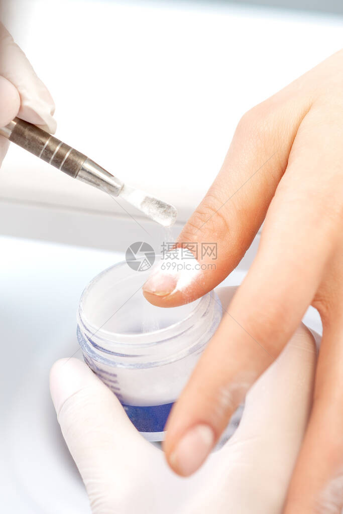 在美容院将丙烯粉贴在一名年轻女子的指甲上的图片
