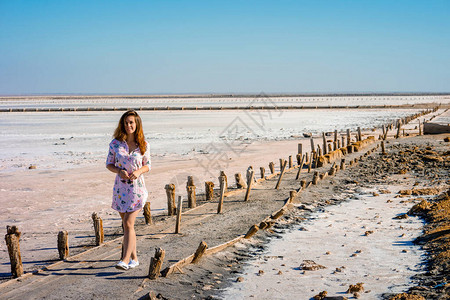 一个穿着裙子的漂亮女人在克里米亚一个干涸的盐湖上散步粉色盐面无图片