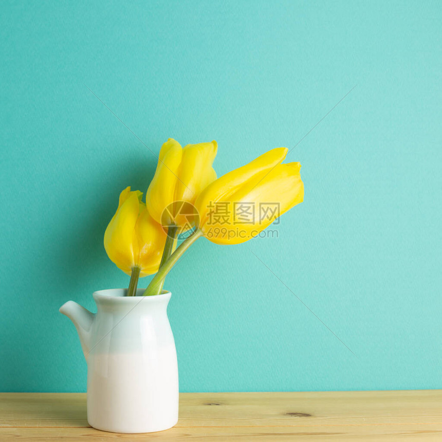 黄色郁金香花在绿色背景的木桌上的花瓶里复制空间图片