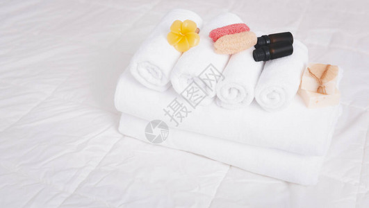 白毛巾有机肥皂乳酪洗涤剂和用干净白色床上的花蜡图片
