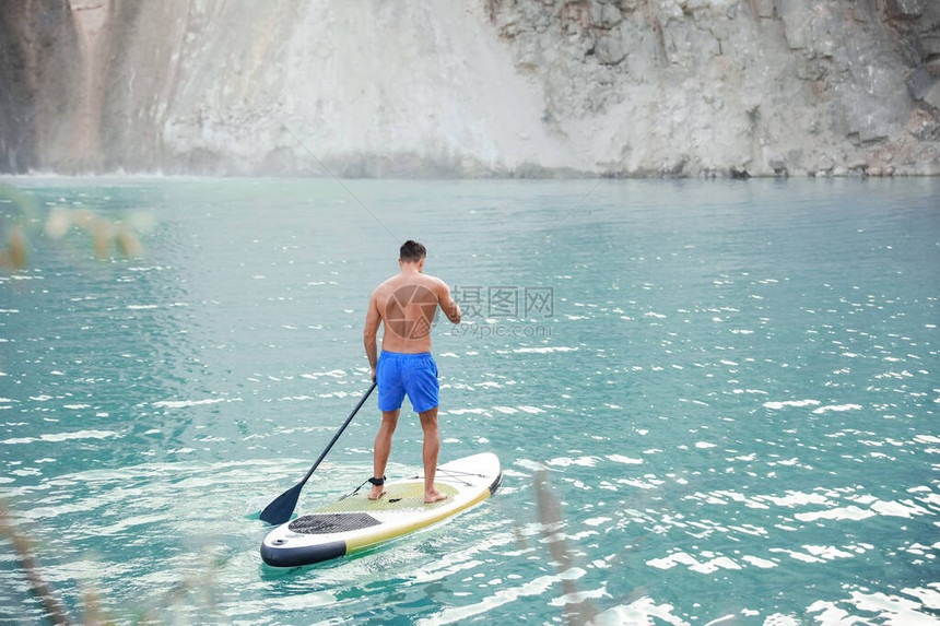 年轻人用桨板在河里冲浪图片