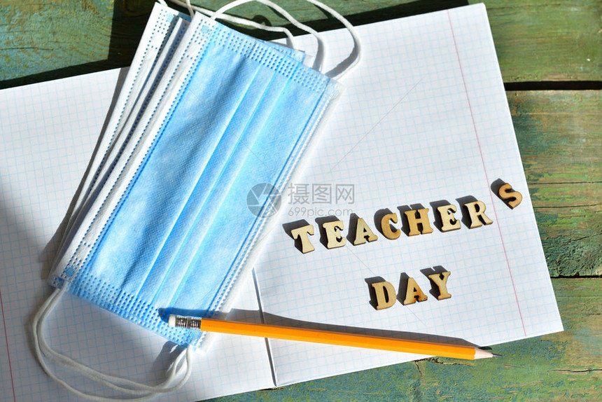 在笔记本上的木制字母教师节教师节快乐铅笔和带复制空间的医用防护面罩图片