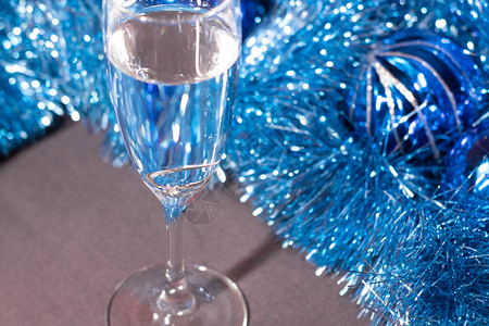 在一个香槟杯中订婚戒指在蓝色闪亮的圣诞树罐子附近背景图片