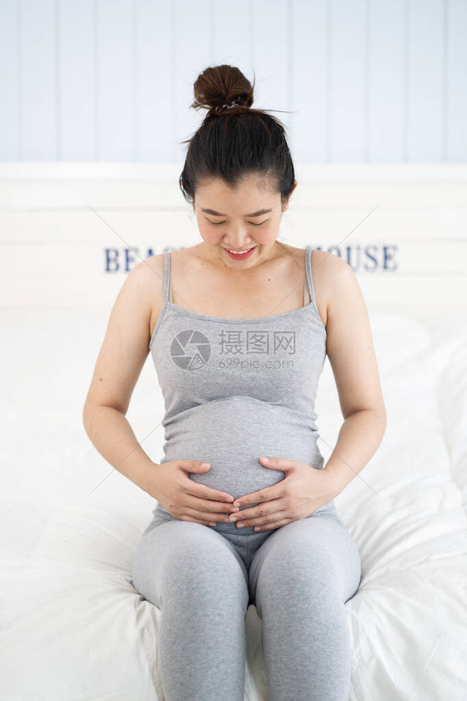 孕妇坐在床上在家里摸肚子图片