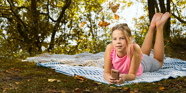 一个小女孩躺在公园的地毯上年轻的女孩躺在秋天的森林里的毯子图片