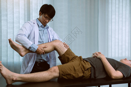理疗师用手握着病人的大腿检查诊所的疼痛和按摩情况图片