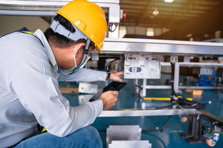 负责安装和检查工业厂传送器电源控制柜的亚洲人机械技工人图片