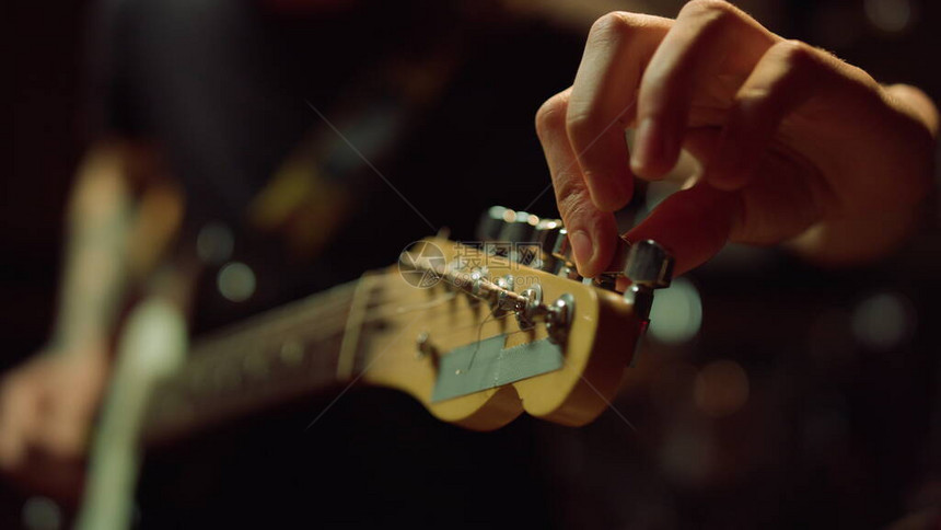 无法辨认的人在音乐工作室调原声吉他音乐厅指板上的宏观音乐家手转动旋钮不知名的吉他手在录音图片