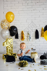 金发男孩生日1年装饰了第一个黑金蛋糕的相片背景图片