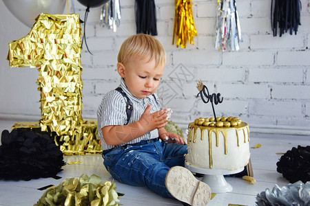 金发男孩生日1年装饰了第一个黑金蛋糕的相片背景图片
