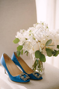 白面上有带扣脚趾的蓝色女子鞋花瓶里有图片