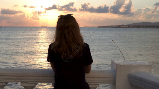 年轻苗条的女孩穿着黑色t恤站在海边图片