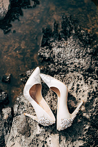 妇女用宝石在岩石海岸用石头为新娘鞋擦奶油图片