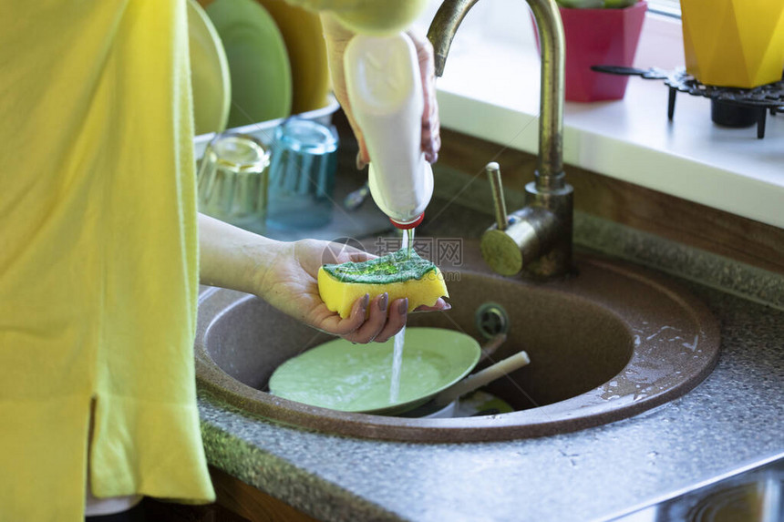 家庭主妇在打扫厨房时洗碗的近景图片