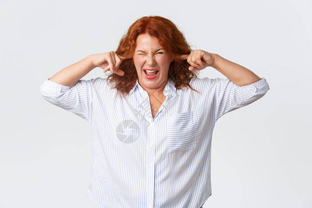 抱怨红头发的中年妇女因可怕的噪音而做鬼脸图片