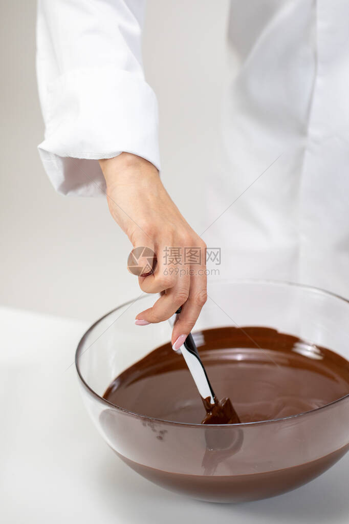 特写女厨师搅拌孤立在白色背景上的深色融化巧克力Chocolatier制作有机苦味不加糖的手工巧克力糖果制作糕点制图片