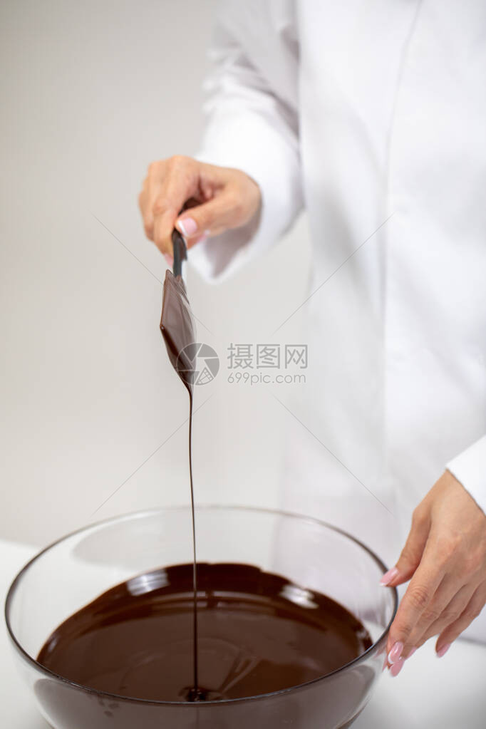 特写搅拌和倒黑融化巧克力孤立在白色背景上Chocolatier制作有机苦味不加糖的手工巧克力糖果制作糕点制图片