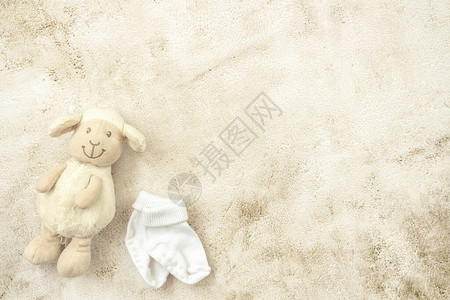 玩具羊羔和婴儿袜在糊面背景上图片