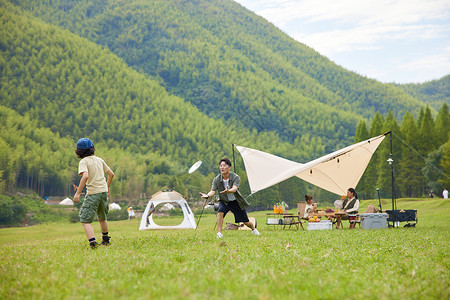 孩子玩耍草地温馨父子户外露营玩飞盘背景