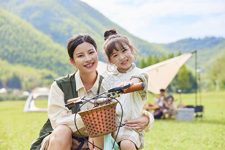 孩子骑自行车户外露营骑自行车的温馨母女背景
