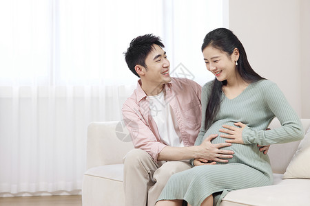 期待的笑丈夫抚摸妻子的孕肚背景
