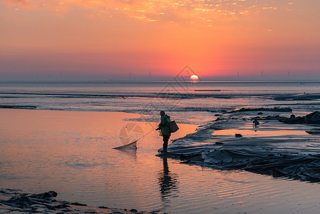 日出时海边捕鱼的渔民背景图片