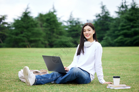 坐在草坪上电脑学习的女大学生图片