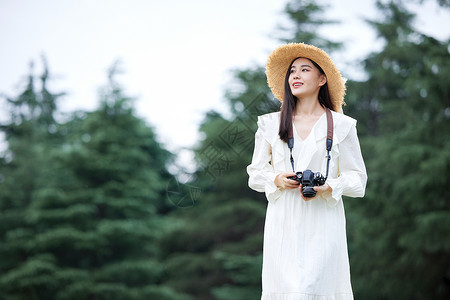 年轻美女拿着相机拍照图片