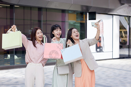 女性逛街购物自拍逛街购物的女性闺蜜使用手机合照背景