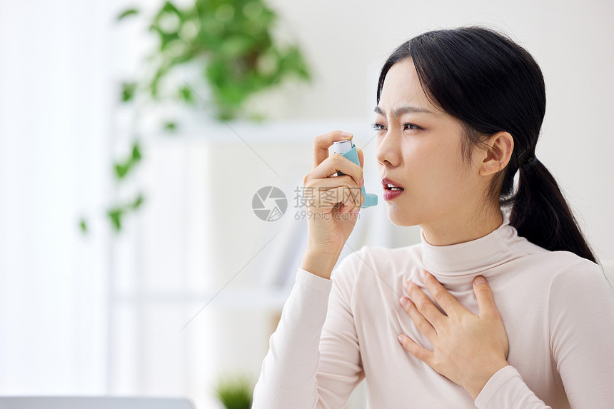 室内生病使用哮喘喷雾的职场女性图片