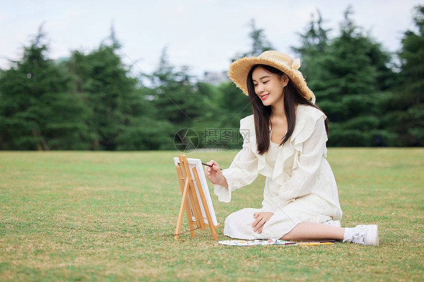 青年女性坐在草坪上绘画图片