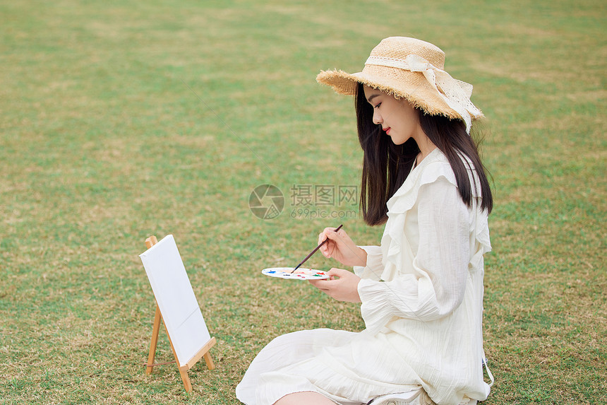 青年女性坐在草坪上绘画图片