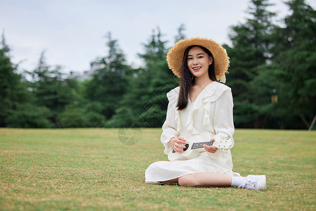 青年美女草坪上谈尤克里里高清图片