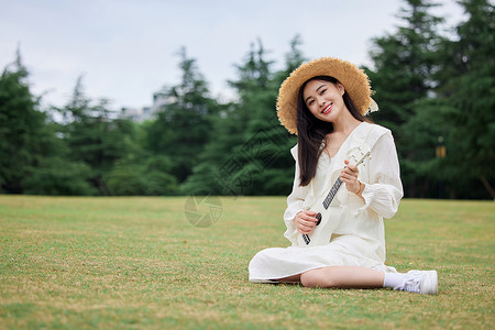 年轻美女草坪上谈尤克里里图片