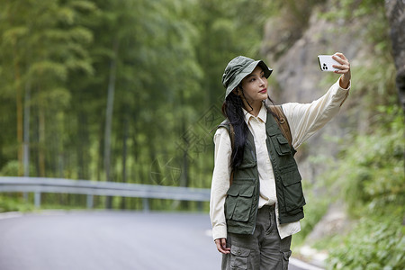 年轻女性户外游玩拿着手机自拍图片