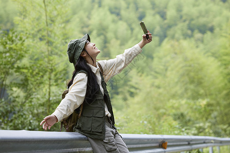 登山手机年轻女性户外游玩拿着手机拍照背景