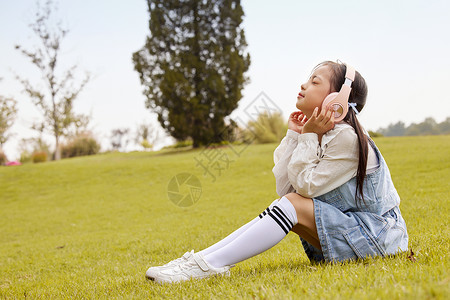 金色耳机素材草地上戴着耳机的儿童背景